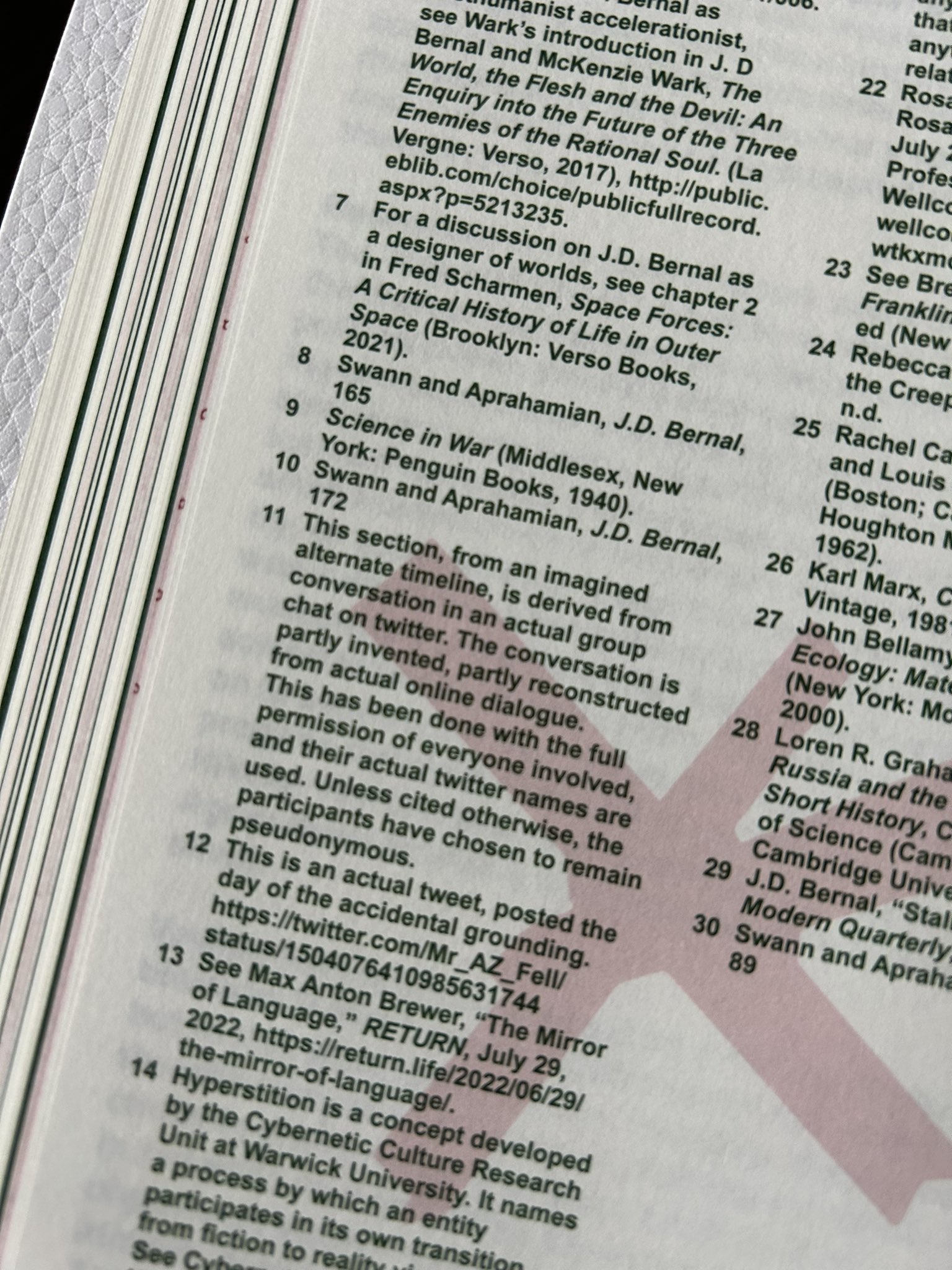 A close-up of a book's footnote page showing numbered citations and references, including mentions of J.D. Bernal, Twitter conversations, and academic sources like "Science in War" and "The Mirror of Language."